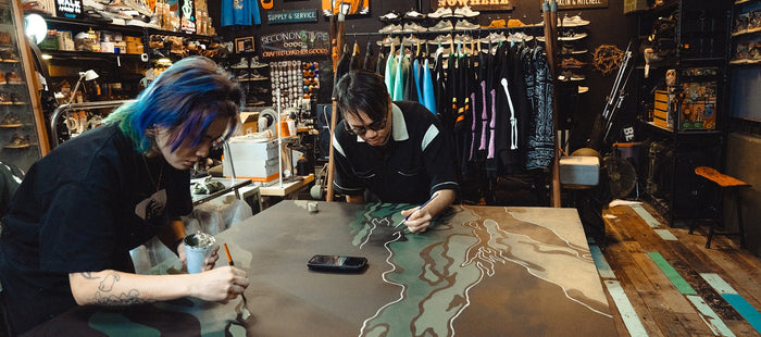 Two individuals painting a large canvas inside a retail store.